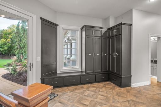 The large mudroom is designed with practicality in mind, featuring built-in lockers and a walk-in closet. Access to the attached 4-car garage. The inclusion of a central vacuum system with convenient kick plates simplifies cleaning and maintenance.