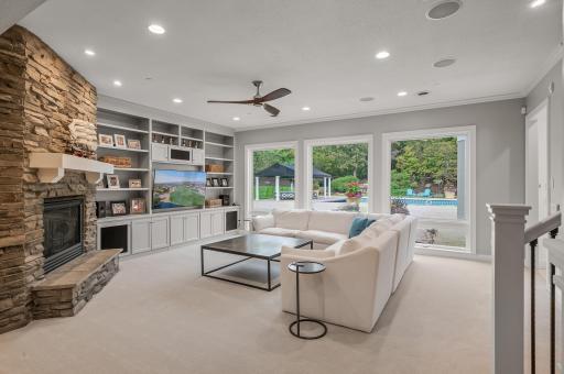 The spacious family room is a welcoming gathering place, featuring a gas-burning fireplace with floor-to-ceiling stone, and a built-in entertainment center.