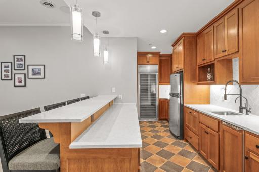 The adjacent recreation room is a hub of entertainment, complete with a well-appointed wet bar. This bar boasts two-tiered quartz countertops with bar seating, a refrigerator, dishwasher drawer, microwave, and a 150-bottle wine cooler.