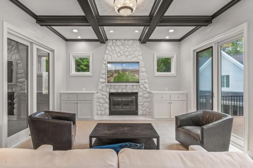 The hearth room offers a cozy retreat with its coffered black ceilings, and another gas-burning fireplace featuring a floor-to-ceiling stone surround.