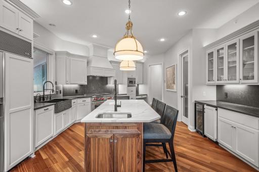 The gourmet kitchen, boasts quartz countertops, under-cabinet lighting, a sizable center island with a prep sink and breakfast bar seating, a spacious walk-in pantry, an ice-maker, and a wine fridge.