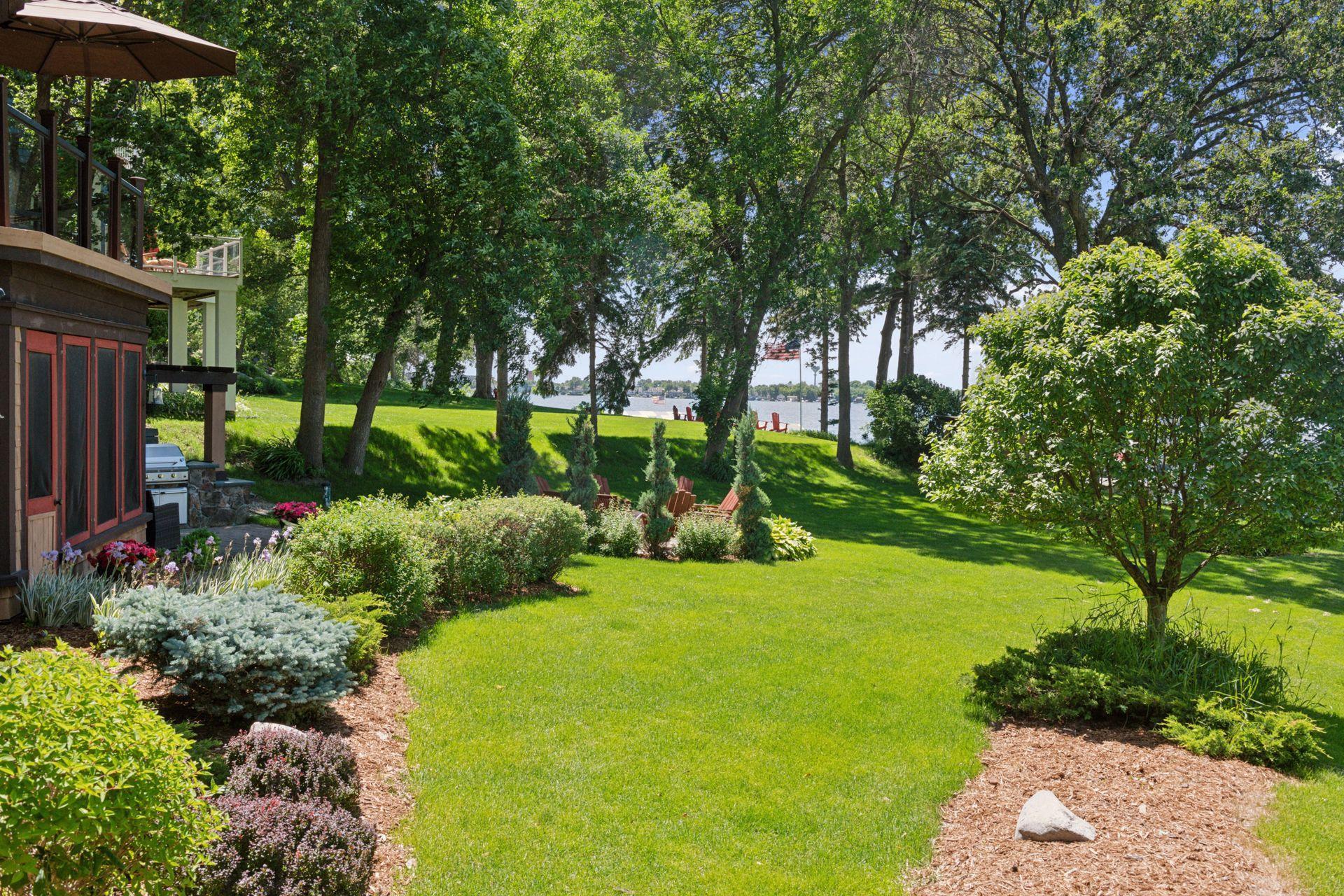 The home is surrounded by professional landscaping featuring evergreen trees, mature shrubs and flowering gardens.