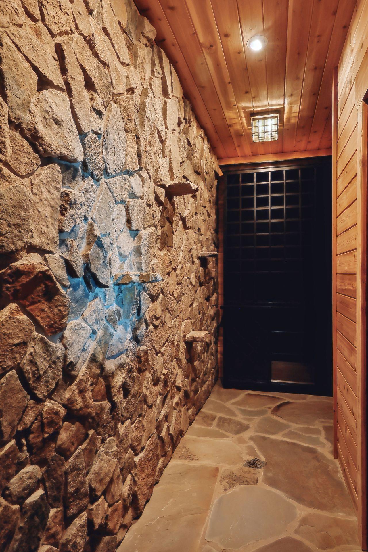 Nestled behind a beautiful door is the Wine Cellar that features flagstone flooring, custom wine racking and stone feature wall with display shelving.