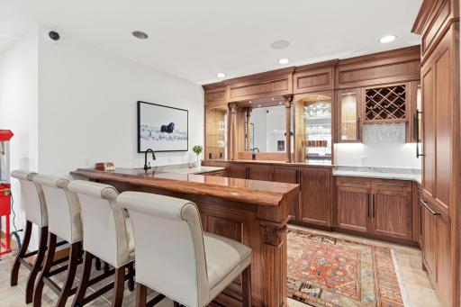 Adjacent to the theatre area is this gorgeous custom-built walnut wet bar. It has a built-in Thermador walnut paneled fridge and dishwasher as well as built-in Sub-Zero ice maker, a stainless steel sink and quartzite countertops.