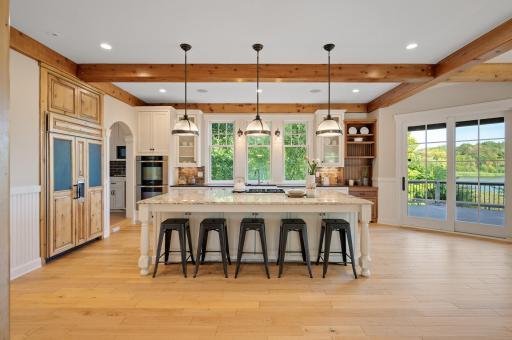 This kitchen boasts crisp white cabinetry, stainless steel and cabinet-front appliances, a Subzero fridge with hidden swivel TV, double wall ovens.