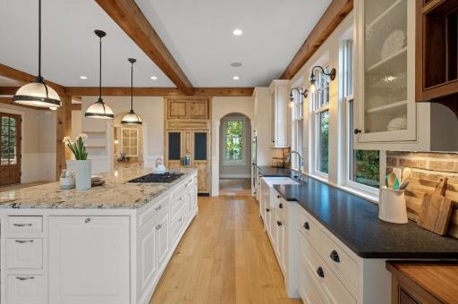 WOLF cooktop on a spacious center island with breakfast bar seating, and brick backsplash complete this perfect entertaining space.
