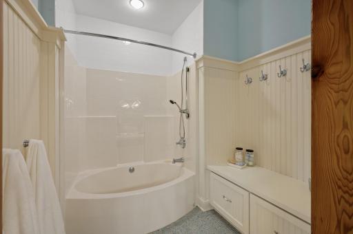 Tub/shower combo, with a nearby built-in bench and convenient laundry chute.