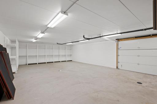 The additional 2-car heated spancrete garage, accessible from the lower level, offers built-in shelves, another utility sink, and extra storage or workspace potential with a convenient 2-car door.