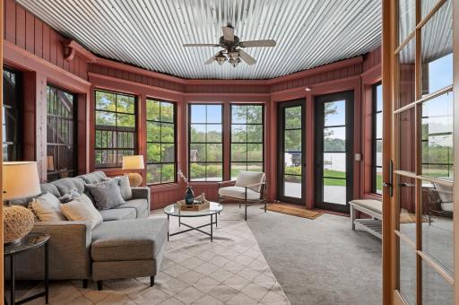 Step through glass French doors into the charming three-season porch, complete with a tin ceiling, heated floors, and cozy red siding. Relax here while taking in views of the beautifully landscaped backyard.