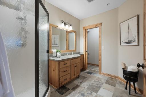 The sleek lower-level bathroom features elegant tile floors, a spacious walk-in shower stall, and a separate water closetâideal for both guests and everyday use.