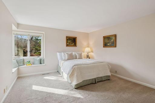 Light and airy this charming guest bedroom features a built-in corner hutch and window seat with a view.