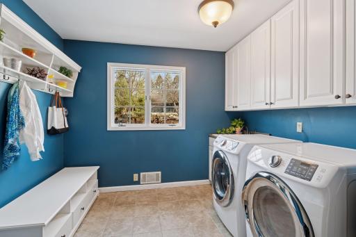 Thoughtfully designed main-level laundry/mudroom featuring durable tile flooring, ample cabinetry for storage, and a washer/dryer set new in 2019.