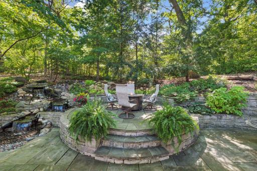 Gather around the cozy backyard firepit beautifully set on an elevated stone platform.