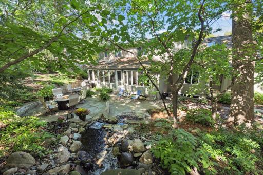 Stunning backyard oasis with an expansive Bluestone patio, retaining walls, landscape lighting and water feature.