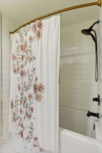Relax in the deep tub surrounded by pristine white tile walls, creating a serene and stylish retreat for your bathing experience.