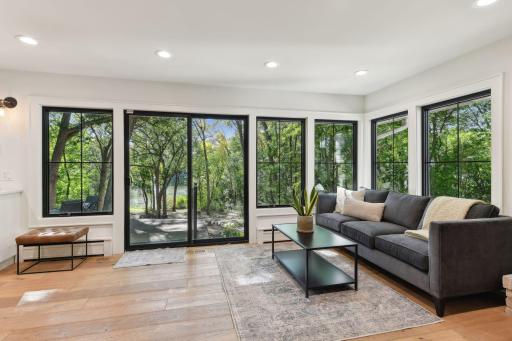 Oversized windows featuring modern black accents, offering stunning views of beautifully landscaped back yard.