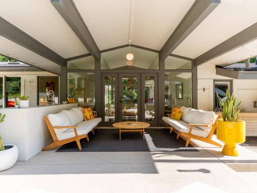 This original MCM covered porch features vaulted ceilings that create an airy, open atmosphere, seamlessly blending indoor and outdoor living.