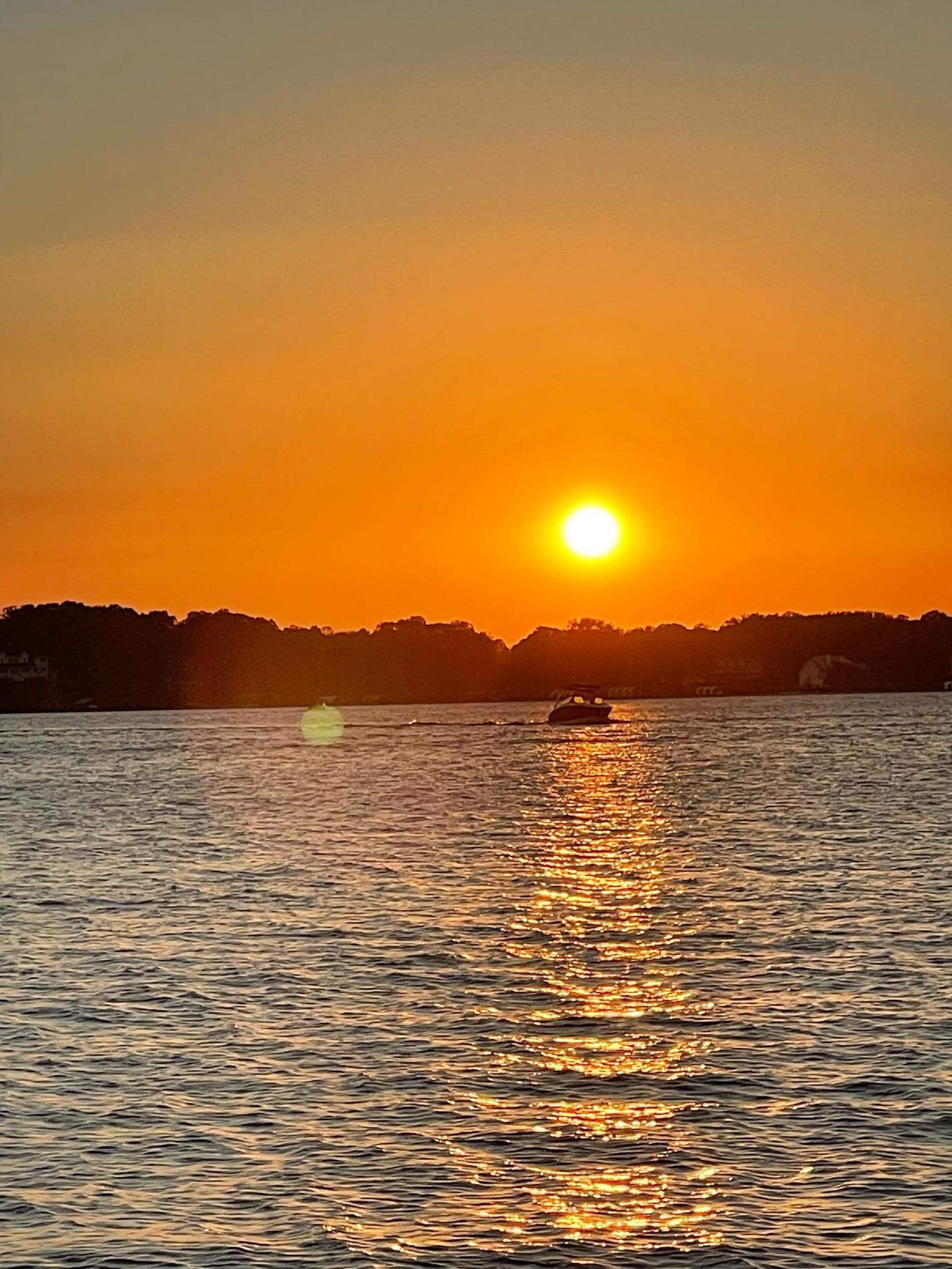 from shore looking at sun setting with boat in photo.jpg