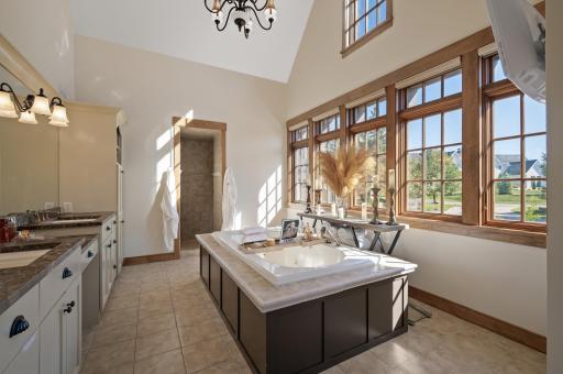 The spa-like ensuite bath is a sanctuary with a soaker tub, a dual-tiled walk-in shower, and abundant natural light in the vaulted ceiling space.