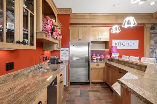 A full wet bar with a granite countertop and full size refrigerator and tile flooring.