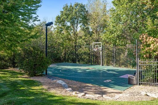This outdoor sport court is a versatile space perfect for a variety of activities, from basketball to pickleball. Surrounded by lush landscaping, the court features a durable surface designed for year-round use.