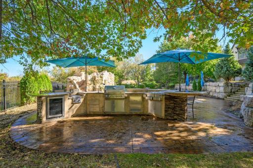 This outdoor kitchen is designed for ultimate entertaining, featuring sleek stainless steel appliances, including a built-in grill, cooktop, refrigerator, wine cooler, and a convenient wet bar.