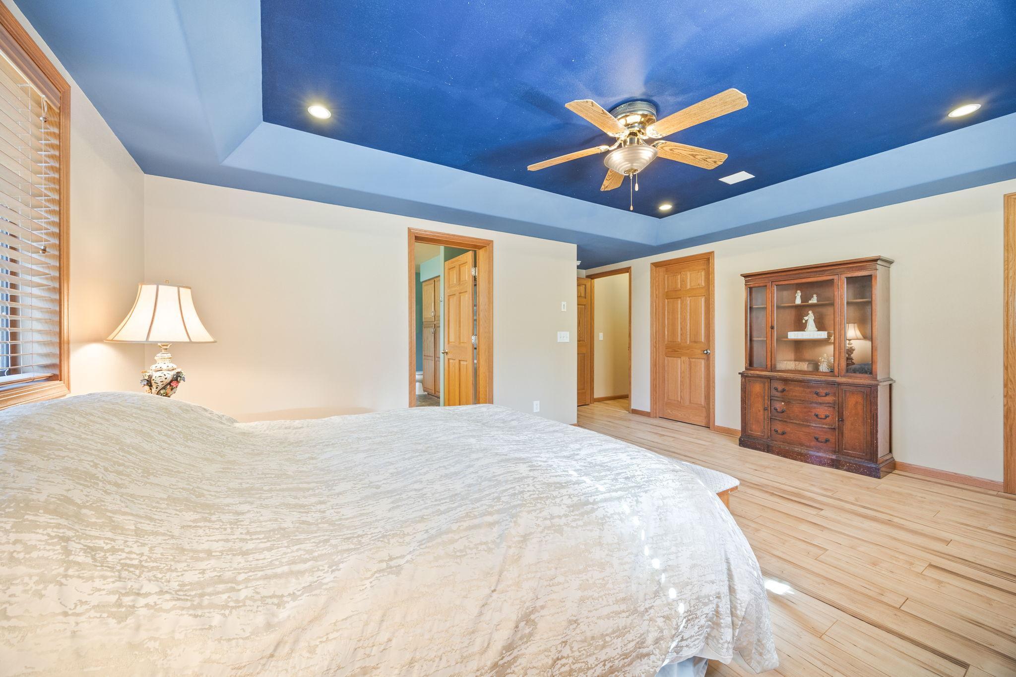 Primary bedroom bedroom with tray vault. Doors leading to primary bathroom, one of the walk-in closets, and hallway.