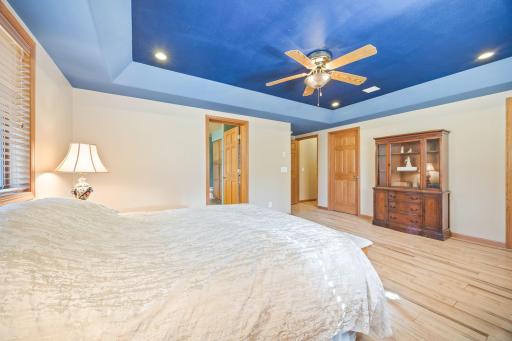Primary bedroom bedroom with tray vault. Doors leading to primary bathroom, one of the walk-in closets, and hallway.