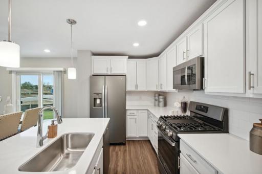 (Photo of decorated model, actual home's finishes vary) Enjoy plenty of seating at the kitchen island and dining area adjacent to the kitchen. Perfect for entertaining or having a family meal together.