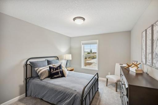 (Photo of decorated model, actual home's finishes vary) One of two generously sized upper level secondary bedrooms with spacious closets.