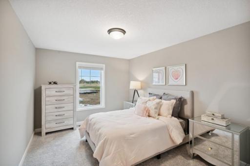 (Photo of decorated model, actual home's finishes vary) The second generously sized upper level secondary bedroom with a spacious closet.