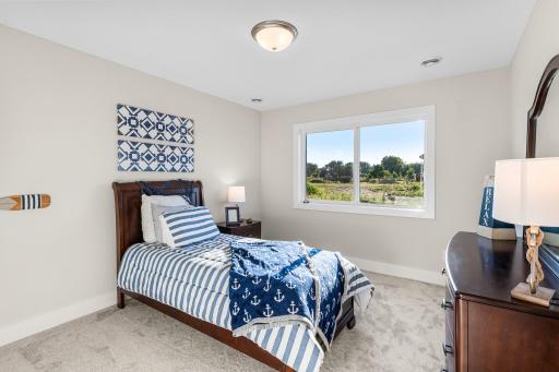 This cozy lower-level bedroom offers a quiet retreat with soft neutral carpeting and a large lookout window that invites natural light.