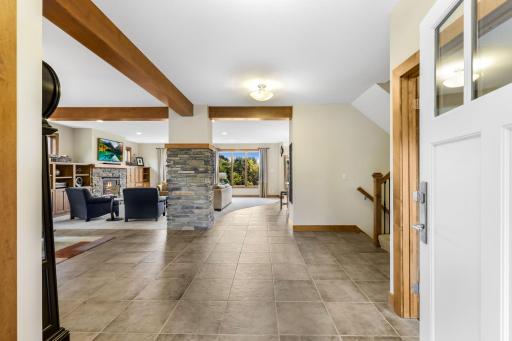 Foyer features open and spacious, tile flooring and stone wrapped column with wood beams that define spaces