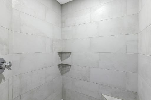 Custom walk-in shower offers full tile surround and a built-in bench