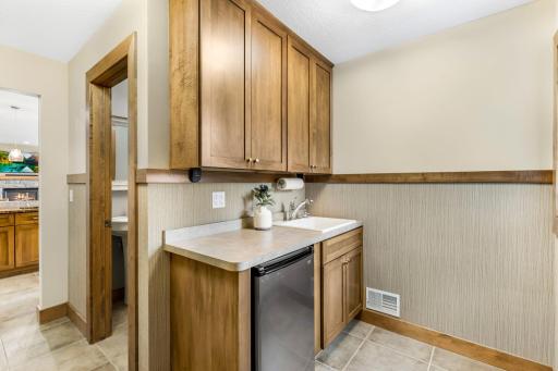 The mudroom features a built-in drop zone with ample cabinet storage and drop-in utility sink and beverage refrigerator. Large walk-in closet with pocket door access (not pictured).
