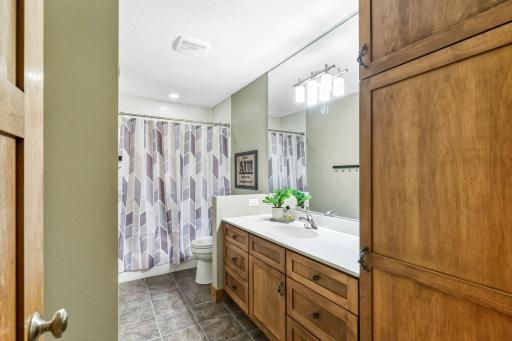 Full Bathroom features large maple vanity and linen cabinet with tile flooring