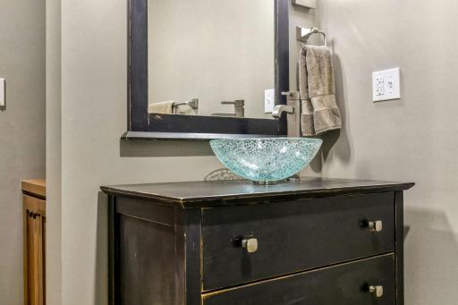 3/4 bathroom features furniture like vanity cabinet with vessel sink and built-in display niche with storage
