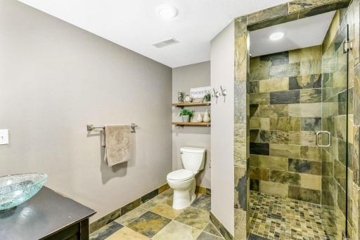Custom shower with slate tile surround and frameless glass door. Slate tile flooring in the bathroom.
