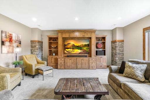 Built-in rustic entertainment cabinets feature storage, display shelving and area for modern size TV. Cultured stone wrapped pillars define the space.