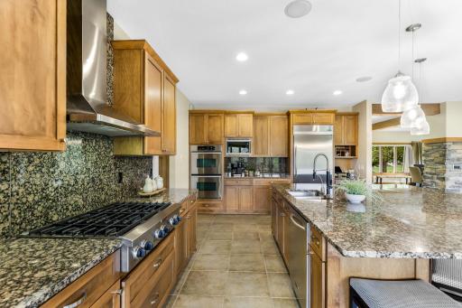KitchenAid stainless steel appliances include a gas cooktop with decorative hood, refrigerator, dual wall ovens, built-in microwave and dishwasher