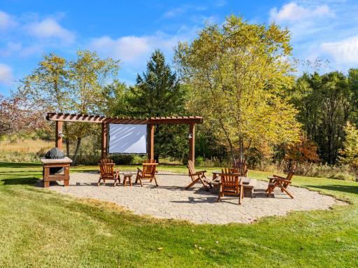 Pergola surround with lighting and a raised fire pit and perfect place for screen and outdoor movies