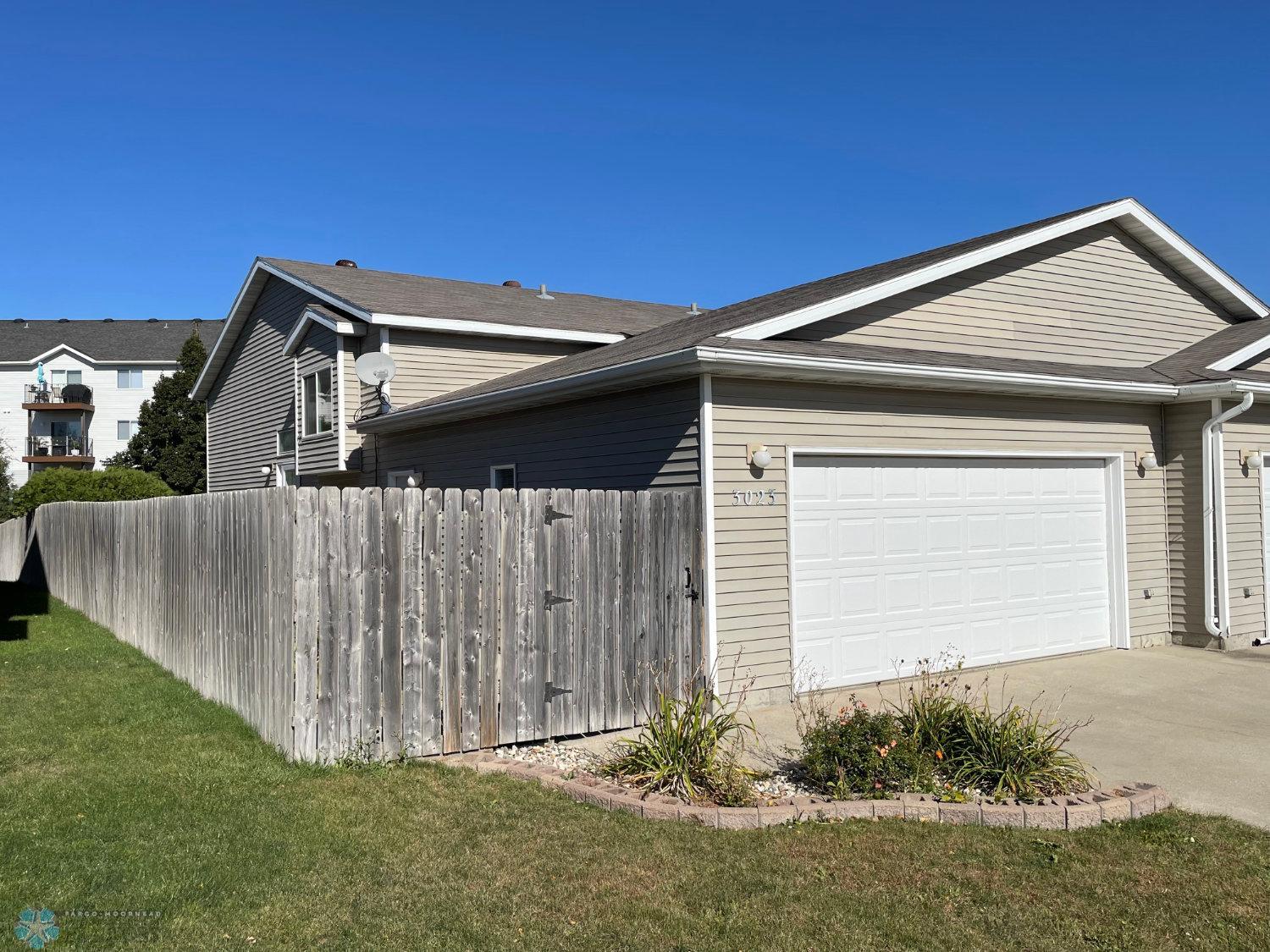 Exterior frVinyl-sided twinhome with fenced yard and a roomy double garage.
