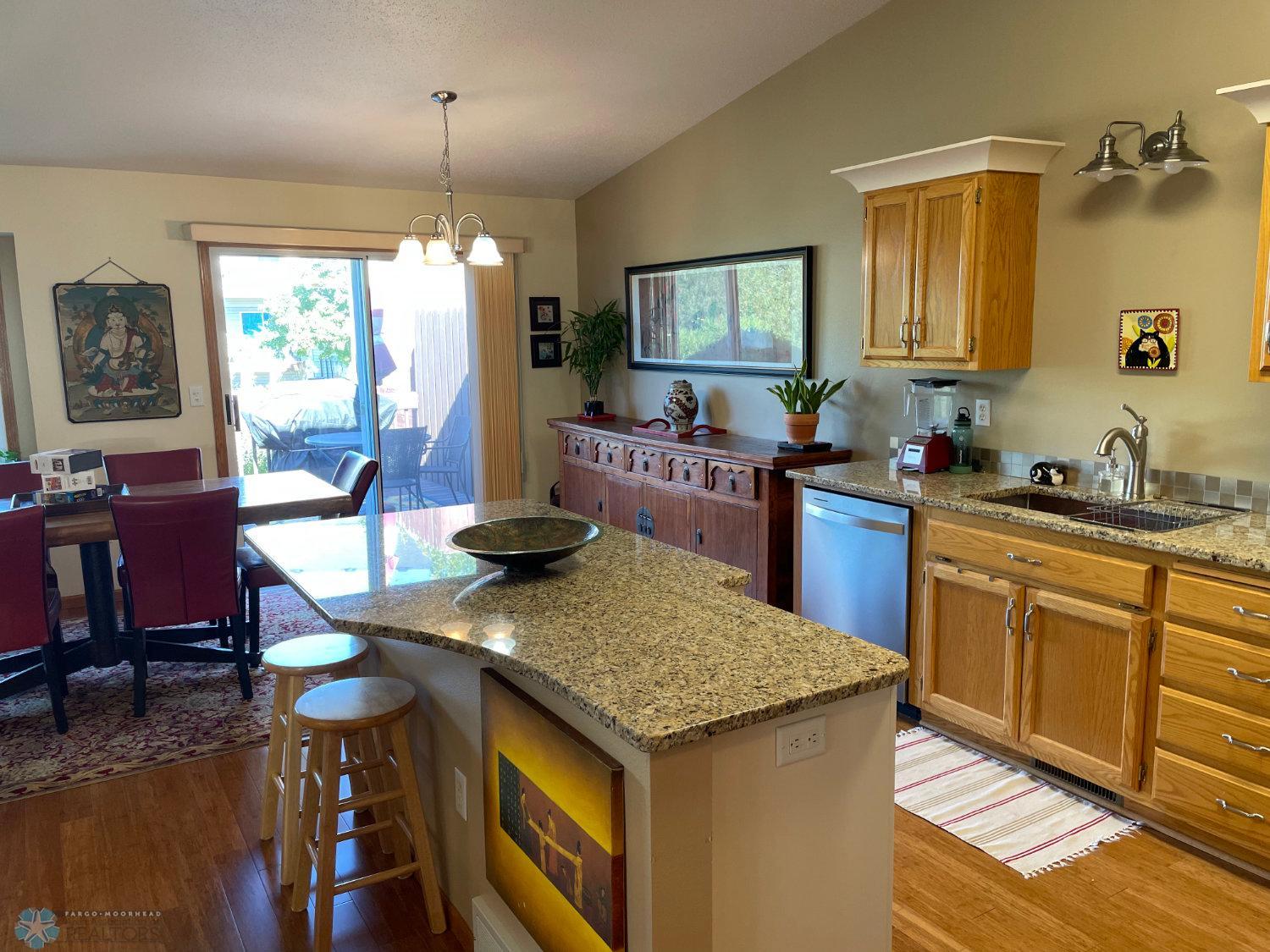 Open remodeled kitchen view to island and dining area. Solid bamboo hardwood floor.