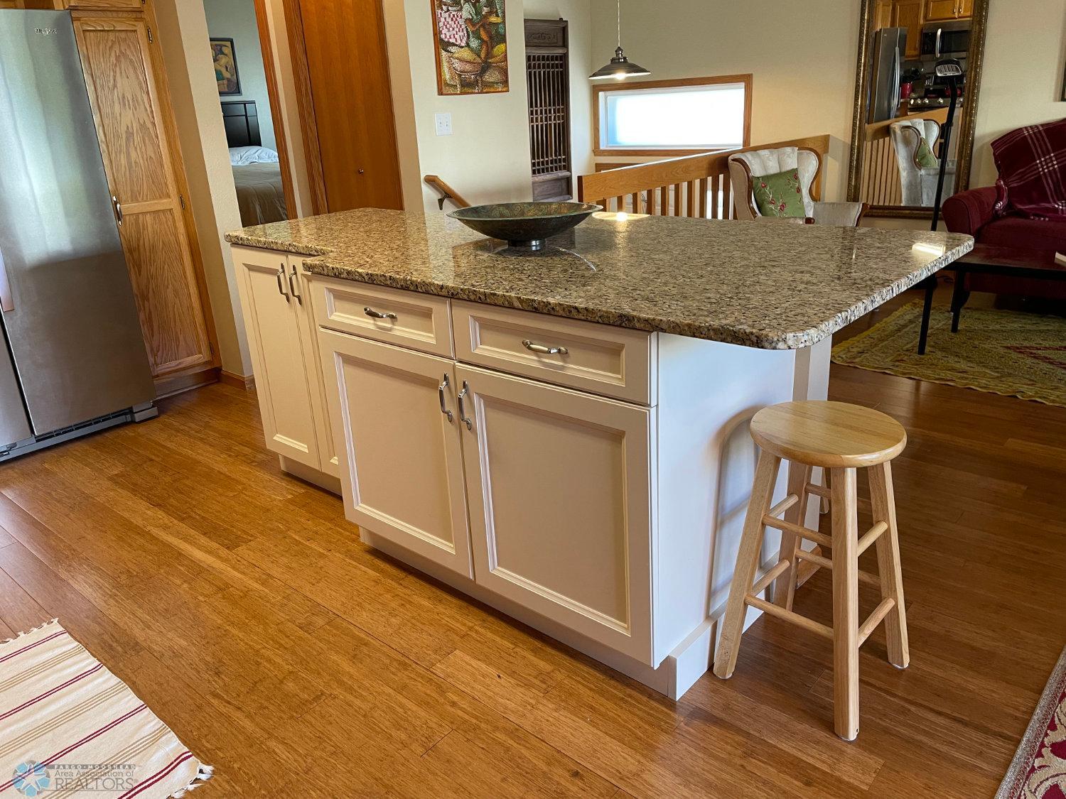 Large kitchen island/breakfast bar with granite counter.