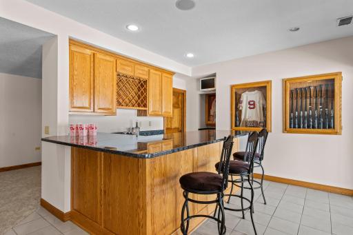 The wet bar, complete with ample storage, a fridge, and microwave, serves as the heart of the space.