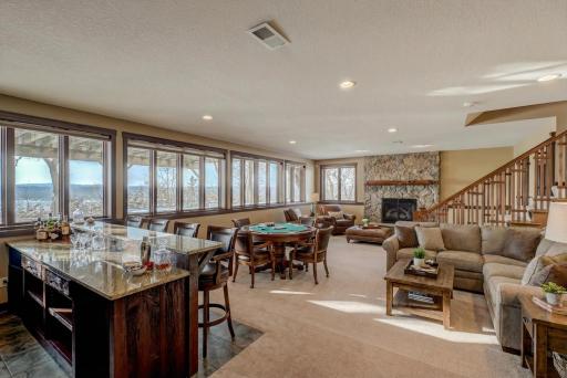 Retreat to the lower level, designed with entertaining in mind, where a striking stone fireplace anchors the light-filled living area.