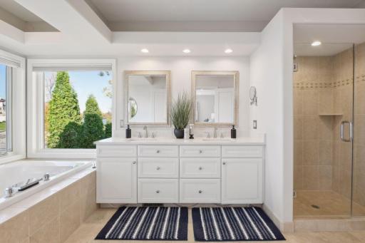 Primary ensuite features a soaking tub overlooking the water, double sink vanity, and a walk-in shower.