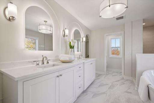 Indulge in the primary bathroom, featuring elegant drawers, arched molding trim, heated floors, and a sleek double sink.