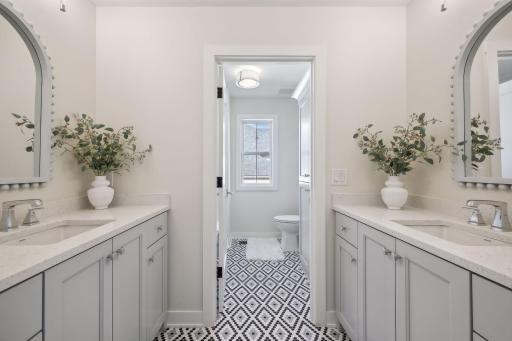 Enjoy the upper level's full bathroom, featuring arched mirrors, dual sinks, and abundant cabinet space.