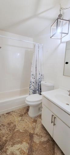 Full bathroom has tile floors and tub surround